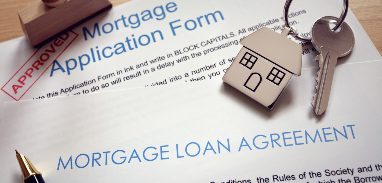 Mortgage loan agreement application with  key on house shaped keyring