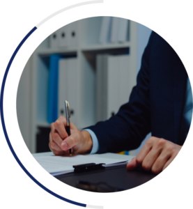 An image of a business person signing a document with a pen. The person is wearing a suite