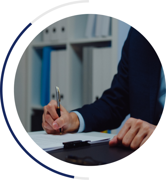 An image of a business person signing a document with a pen. The person is wearing a suite