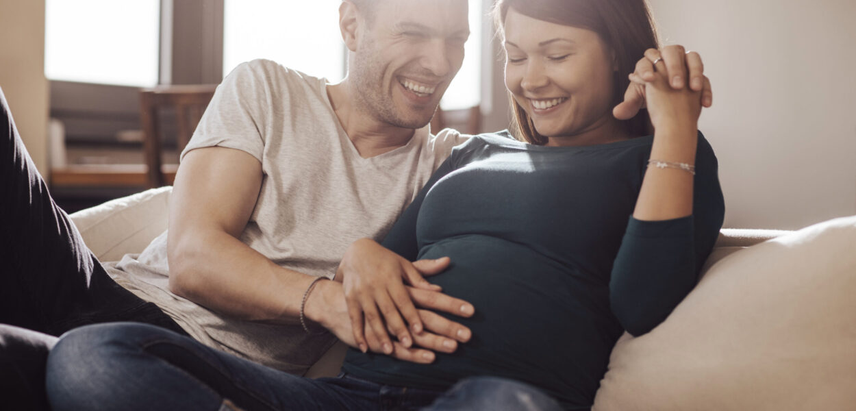 Husband touching wife's stomach, trying to feel baby.